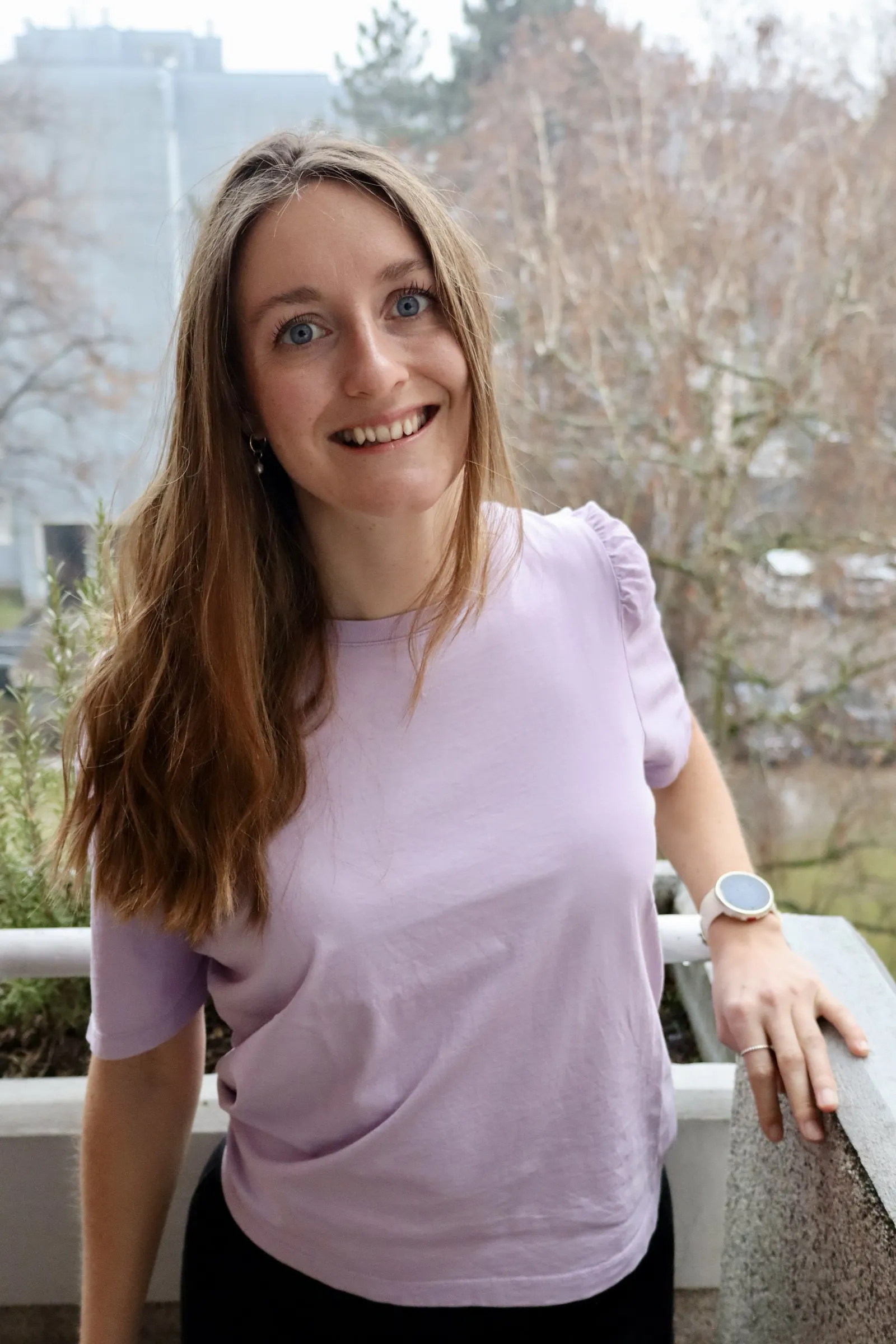 Kristina Haslinger steht auf einem Balkon, im Hintergrund Bäume