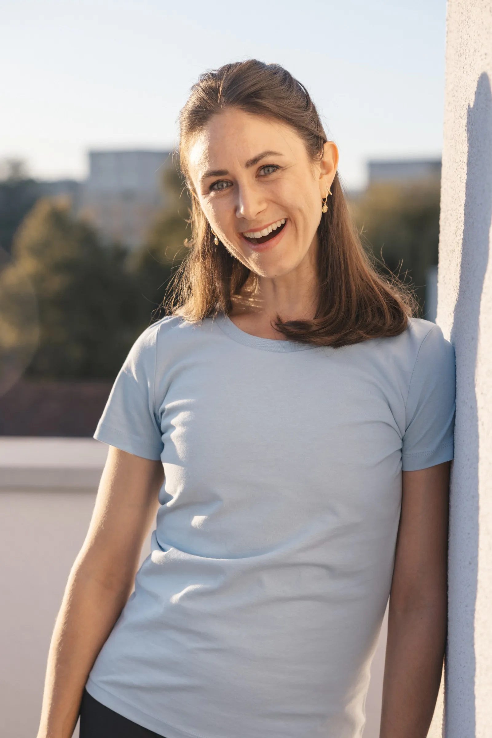 Johanna Penninger lehnt lachend an einer Wand auf der Dachterrasse der Praxis