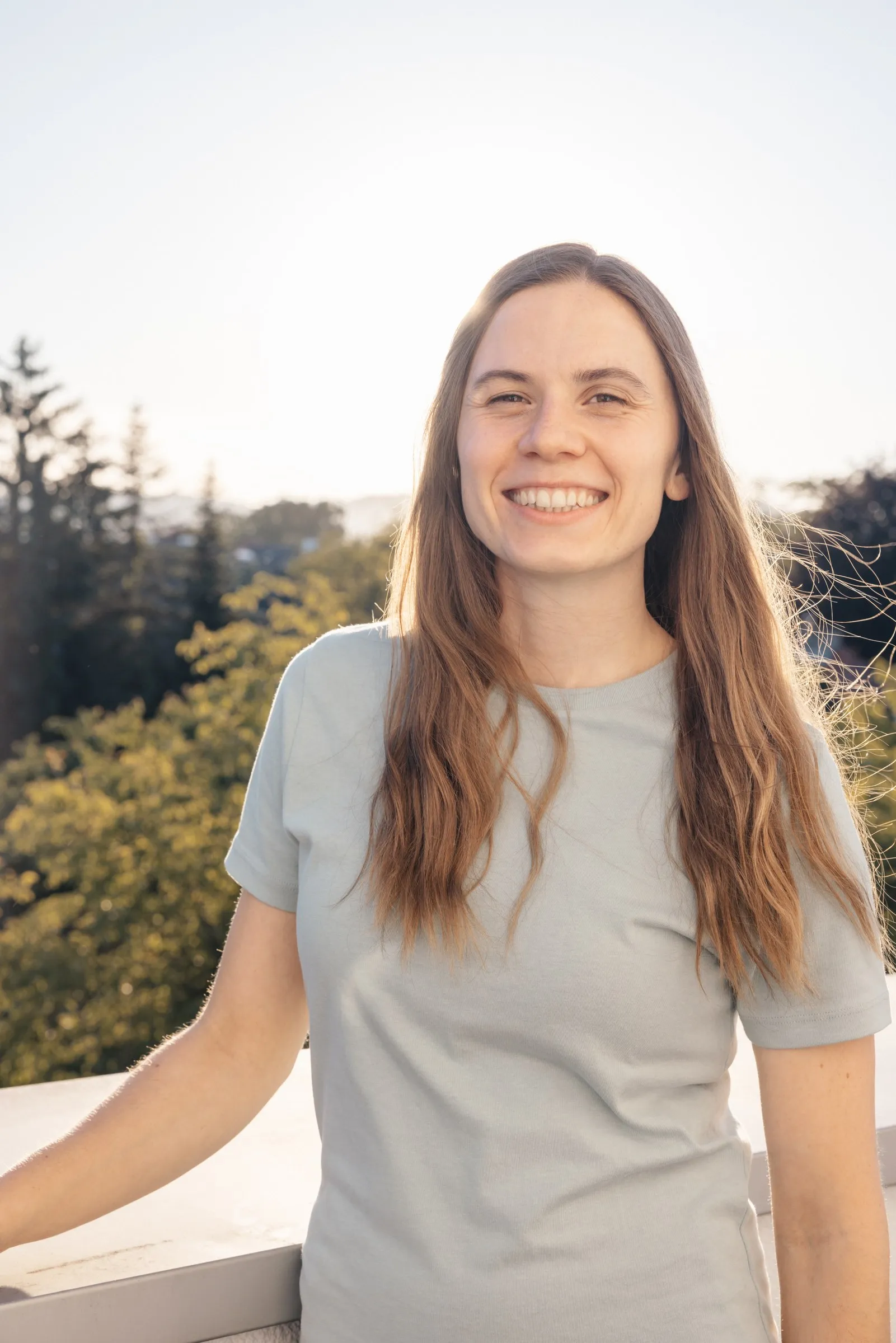 Theresa Ulz lehnt am Geländer der Dachterrasse, im Hintergrund Bäume