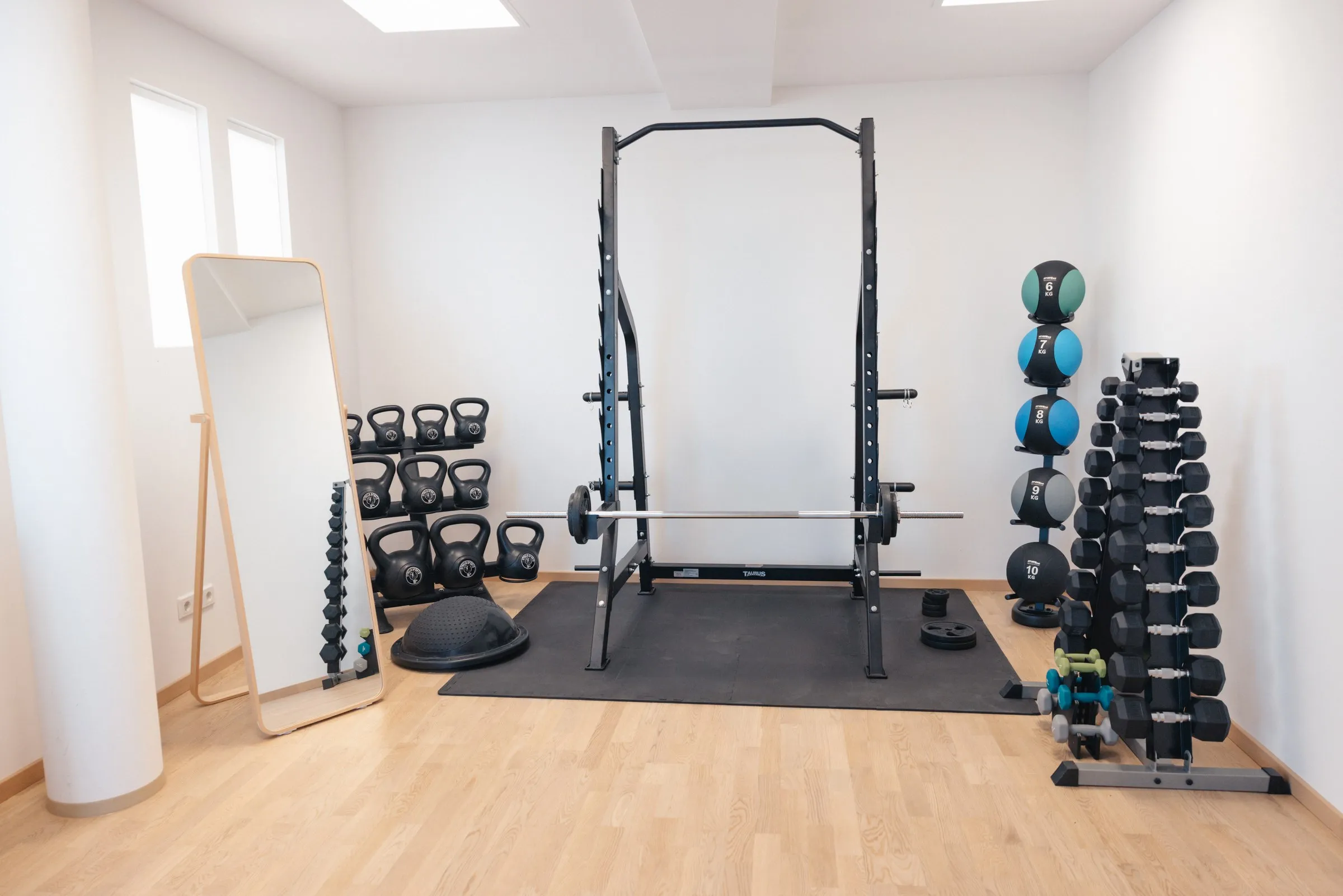 Trainingsraum mit Squat Rack, Langhantel, Kettlebells und Kurzhanteln